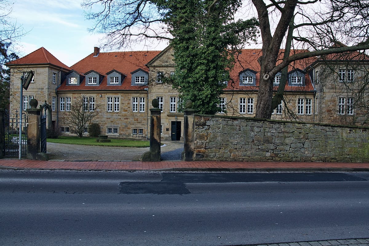 Kloster Barsinghausen: historisches Klostergebäude aus Bruchstein mit Kirchturm hinter dem gepflegten Klostergarten am Fuß des Deisters