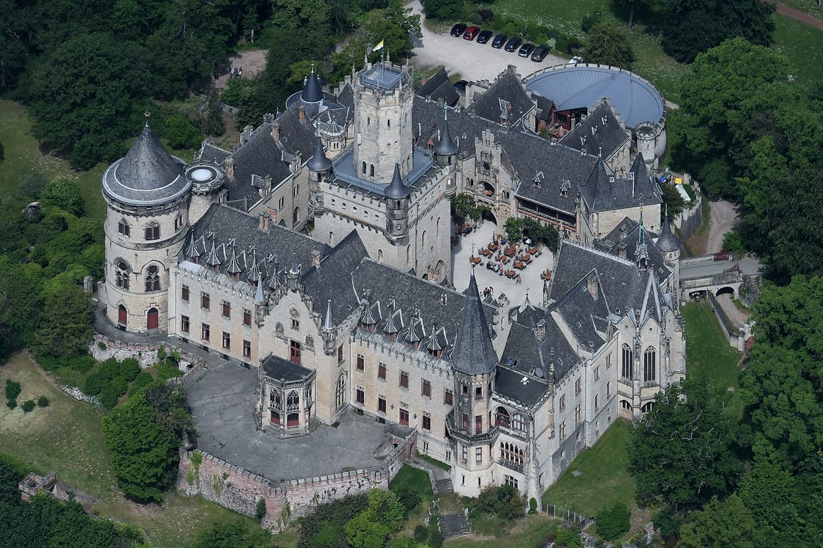 Luftaufnahme von Schloss Marienburg bei Nordstemmen: das neugotische Schloss mit Türmen, Zinnen und Innenhof auf dem bewaldeten Marienberg
