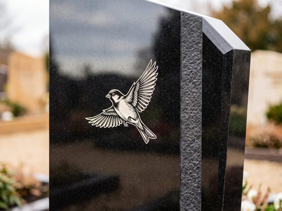 Grabstein aus poliertem schwarzem Granit mit heller Inschrift und Vogel-Motiv
